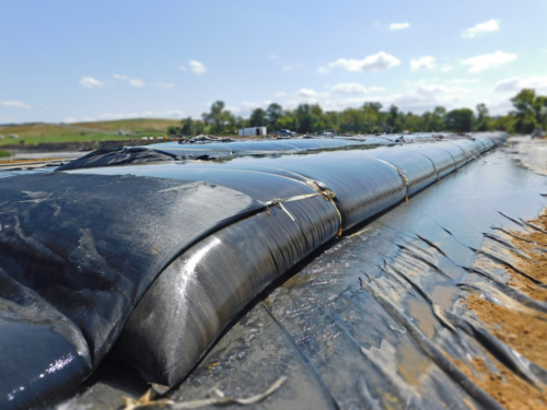 Geotextile tube, deployed, plumbed and partially filled with coal ash