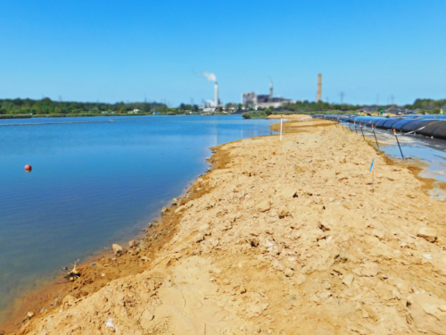 Geotextile tube wall being installed along the perimeter of the coal ash pond